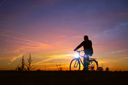 骑自行车的人。车手剪影在复古自行车与日落天空背景。健康的娱乐和活动