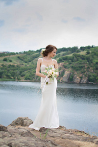 美丽的新娘穿着婚纱时用束鲜花