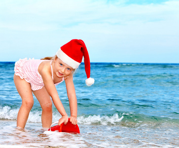 在海滩上玩的圣诞老人帽子儿童