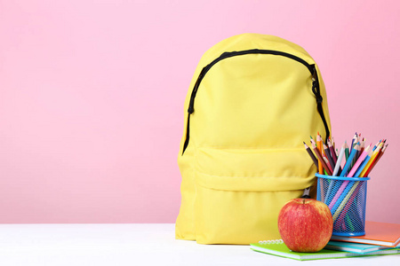 黄色背包与学校供应在粉红色背景