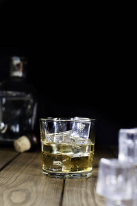 玻璃威士忌与冰, 冰块和瓶子在木桌和黑色背景