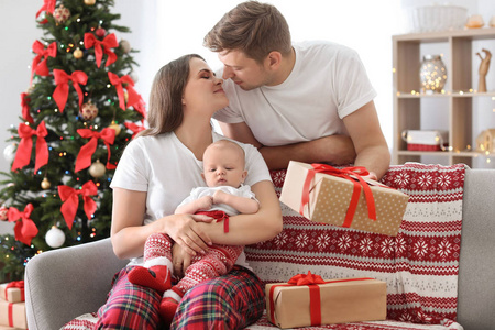 愉快的夫妇与婴孩一起庆祝圣诞节在家里