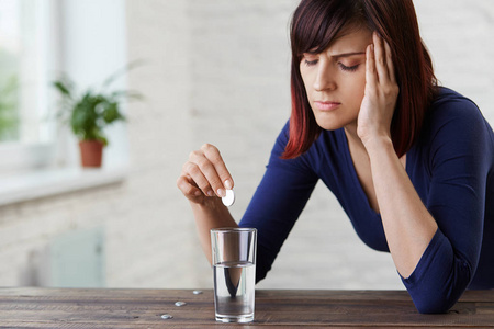 握住手指到她的寺庙和关闭眼睛从痛苦, prepairing 吃药