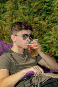 年轻的成人坐在外面享受夏日的阳光与啤酒在花园里