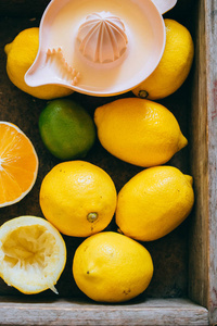 柠檬, 石灰, 橘子在一个木箱里, 一个柑橘榨汁机。新鲜柠檬水