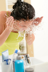泼水在浴室中脸上的女人