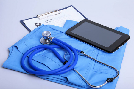 躺在蓝色的医生统一特写的医用听诊器头。医疗工具和仪器商店，运用工作区中，物理，血压测量概念
