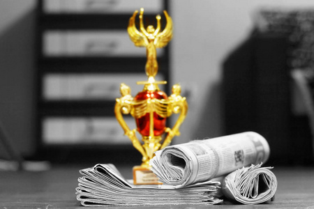 一叠报纸和金奖杯, 商业胜利的概念