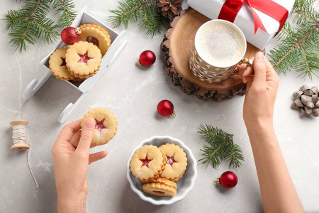 妇女吃传统的圣诞 Linzer 饼干与甜果酱在餐桌上, 顶部视图