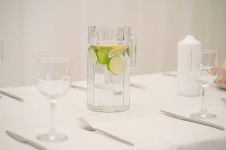一桌配有白色桌布和空盘子的美味的新鲜水, 配有石灰和薄荷。