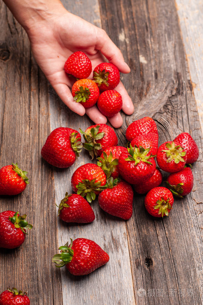女人手里拿着新鲜的草莓木桌上的草莓
