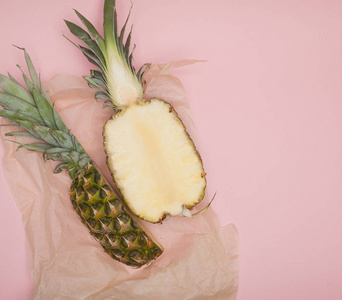 半切多汁的菠萝在柔和的粉红色背景。极小的夏天概念