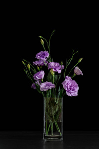 花瓶与美丽的洋花在桌子上反对黑暗背景
