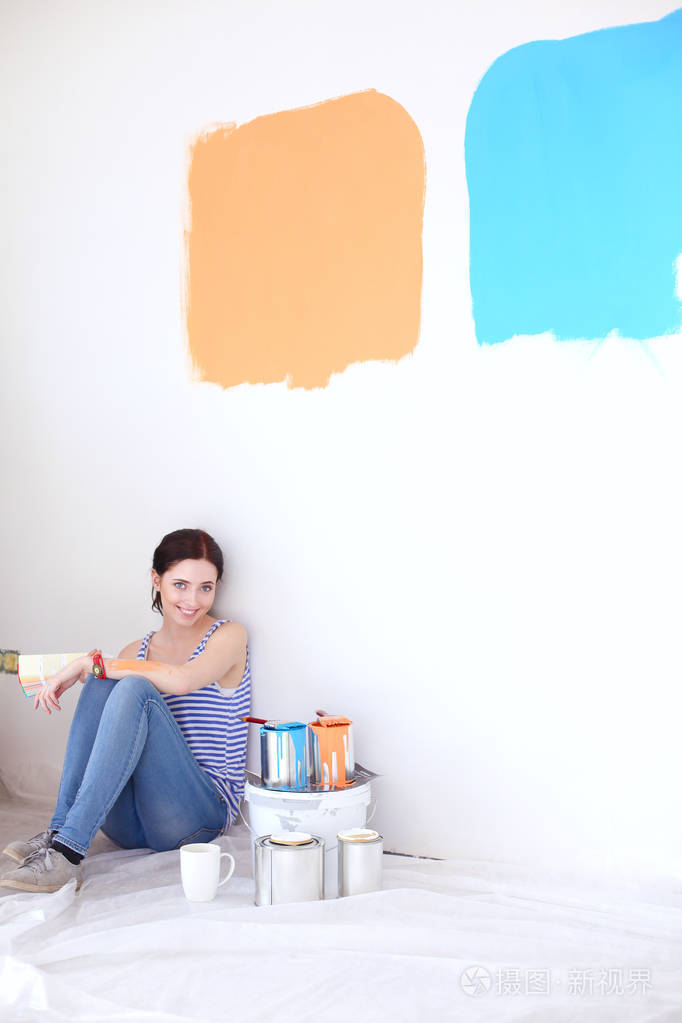 女人选择油漆颜色从色板为新回家坐在木地板上。在房子里的女人