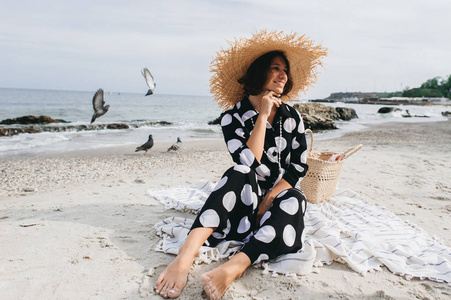 妇女在暑假穿着草帽和海滩礼服享受风景在海