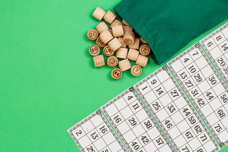 木桶与布袋和游戏卡的绿色背景。棋盘游戏。具有复制空间的顶部视图