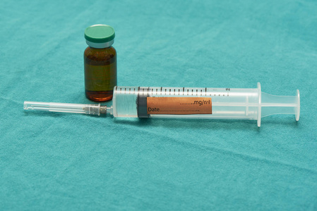 手术室绿色布上装有麻醉药品和药物瓶的塑料注射器