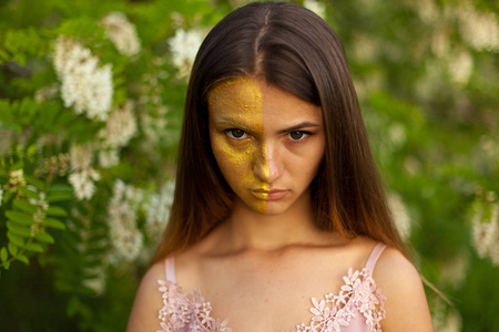 一个美丽的年轻女孩的特写画像在白色相思在春天半面孔金黄化妆