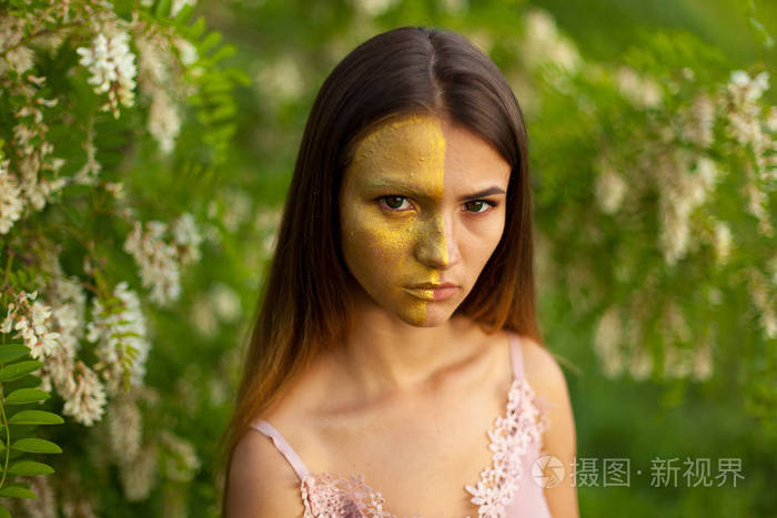 一个美丽的年轻女孩的特写画像在白色相思在春天半面孔金黄化妆