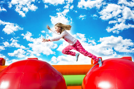 跳跃的乐趣快乐的小女孩有很多的乐趣, 而跳跃从球到球在充气城堡照片