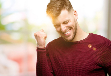 英俊的年轻人高兴和兴奋地庆祝胜利表达了巨大的成功, 力量, 能量和