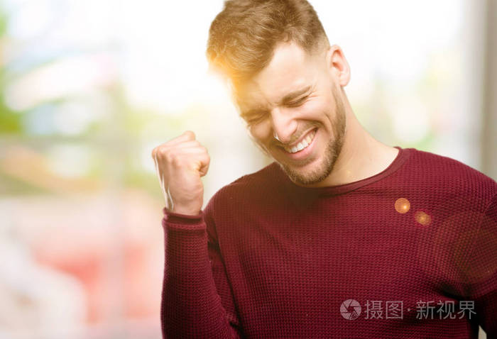 英俊的年轻人高兴和兴奋地庆祝胜利表达了巨大的成功, 力量, 能量和