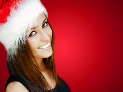 美丽的女人戴圣诞老人帽子微笑到相机