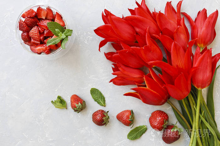 在灰色背景下, 以美丽的红色郁金香花为食鲜草莓的特写。顶部视图, 选择性焦点