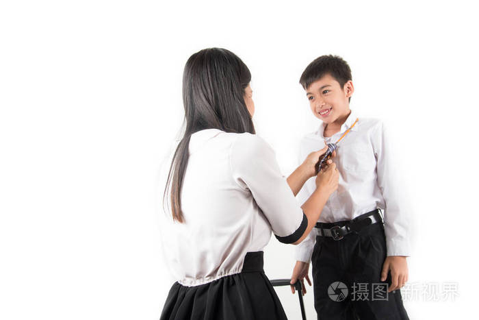 母亲正在帮助学校男孩穿颈领带准备上学的第一天