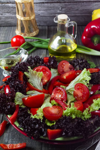 带西红柿和胡椒的沙拉在一个黑色的木质背景盘子里