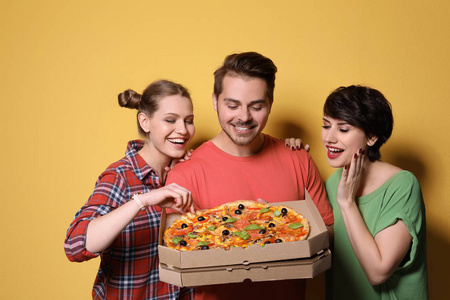 小组的朋友与美味的比萨饼的颜色背景