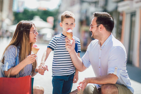 快乐的家庭有乐趣在外面购物并且吃冰淇淋
