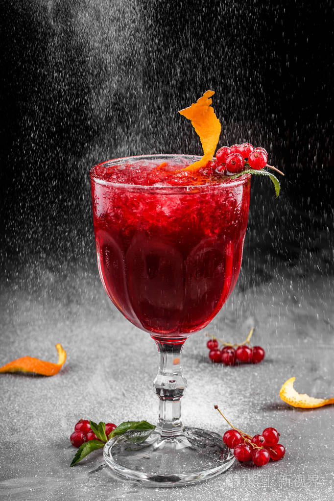 冷红色鸡尾酒与红色醋栗橙色和冰在高玻璃在黑暗的背景夏日饮品和酒精