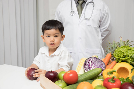 健康和营养的概念。孩子学习营养与医生选择如何吃新鲜水果和蔬菜
