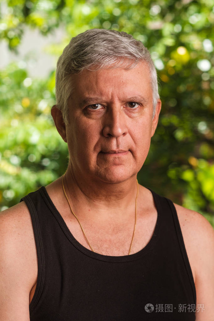 具有绿色背景的英俊的中年男子室外肖像