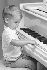 小男孩在家里弹钢琴。音乐的概念