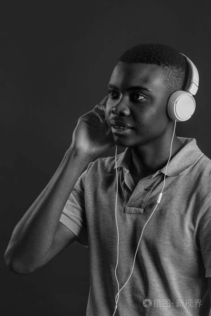 闭上眼睛, 戴着耳机, 听最喜欢的音乐的深色皮肤的人的肖像