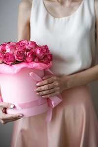 特写照片的华丽花束粉红色玫瑰在一个帽子盒。女性手指甲, 指甲油艺术