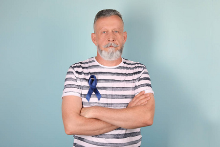 成熟的人与蓝色丝带在颜色背景。泌尿外科癌症意识
