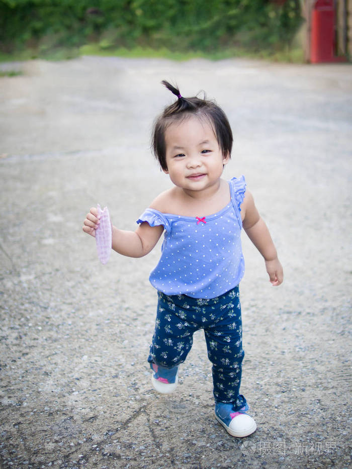 亚洲小女孩在公园里吃零食照片-正版商用图片058o28-摄图新视界