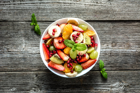 新鲜水果沙拉, 在木制背景的碗顶部视图, 素食概念