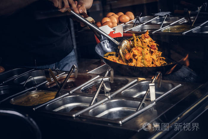 库克在炒锅里用香料和调味汁煎蔬菜亚洲餐厅的烹饪过程