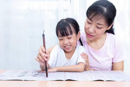 亚洲华人母亲教女儿在家练习中国书法