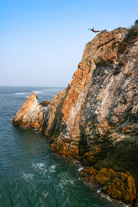 悬崖潜水员跳跃从岩石山到海在阿卡普尔科, 墨西哥