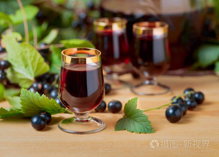 自制黑醋栗甜酒和新鲜浆果在树枝上木质背景