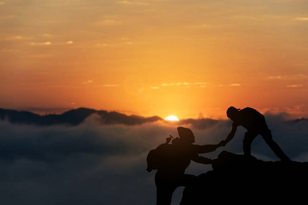两个朋友互相帮助设法到达山顶在美妙的夏天日落期间