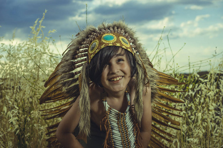 印度在日落时小男孩在日落时身着美国印第安人的衣服, 戴着印度羽毛羽