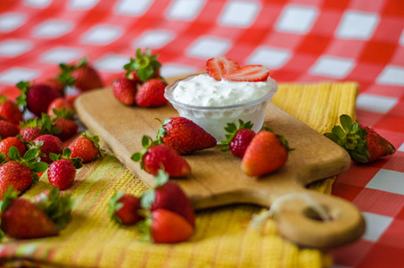 酸奶在小玻璃碗与草莓周围, 在木制的切削板