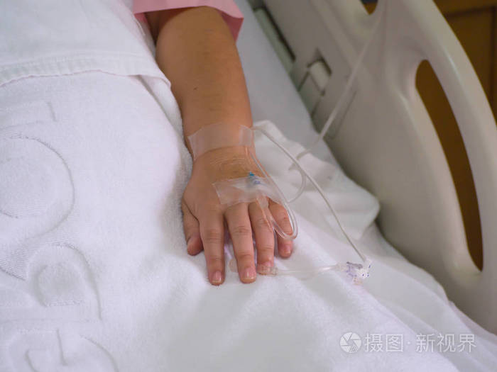 病人在输液中接受盐水溶液, 在医院的一个女人的手关闭盐水解决方案