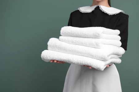 年轻女服务员, 有一堆干净的毛巾在彩色背景下